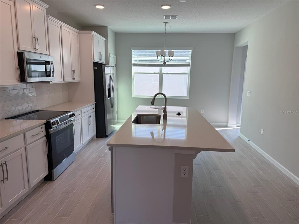 611 Pothos Street Apopka, FL 32703 - Photo 5 of 34 a kitchen with kitchen island granite countertop a sink cabinets and stainless steel appliances
