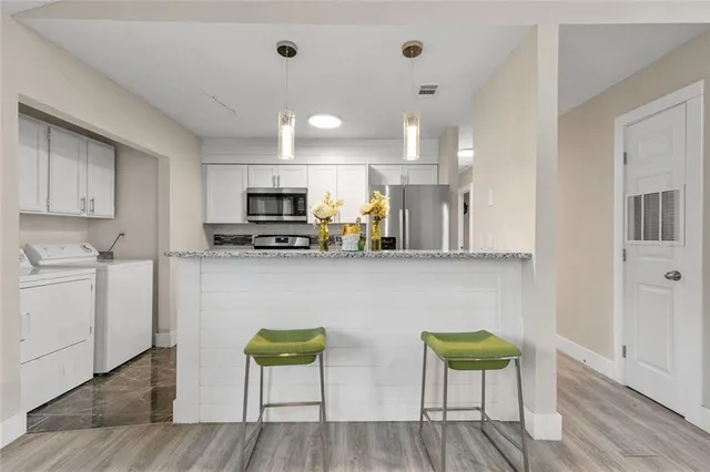 a kitchen with stainless steel appliances granite countertop a stove a sink a microwave a dining table and chairs with wooden floor