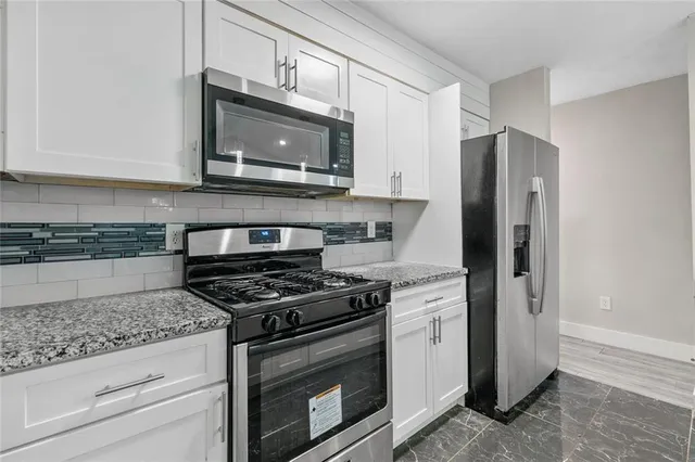 a kitchen with stainless steel appliances granite countertop white cabinets and a stove a refrigerator with a granite counter tops