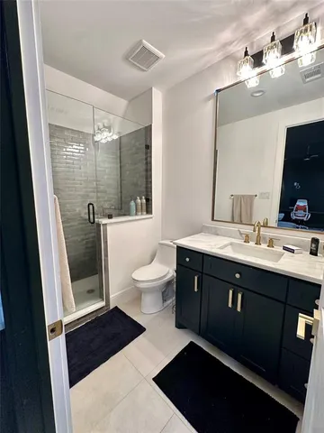 a spacious bathroom with a double vanity sink a toilet a mirror and shower