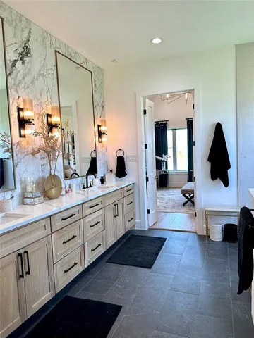 a spacious en suite bathroom with double vanity mirrors and window