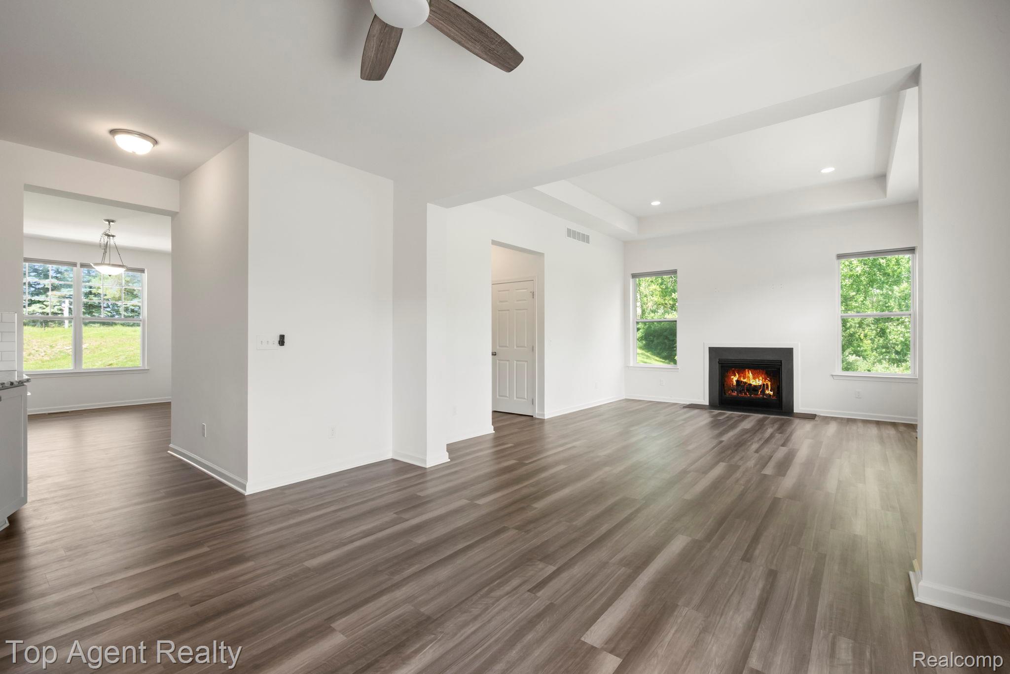 63770 Dequindre Road Washington, MI 48095 - Photo 16 of 61 Spacious living area featuring wood-finish flooring, a contemporary fireplace, and a tray ceiling
