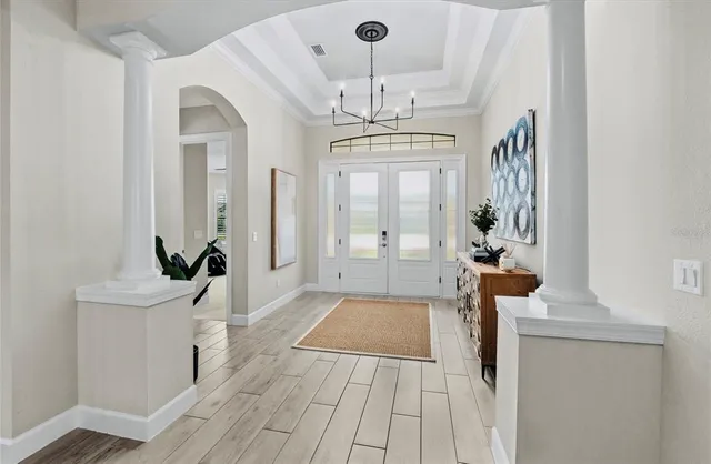 a view of a hallway with wooden floor and a chandelier