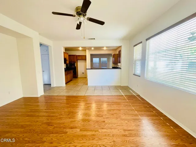 a view of an empty room with kitchen and a window
