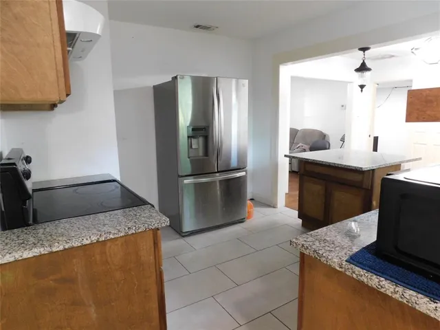 a kitchen with kitchen island granite countertop a sink stove and refrigerator