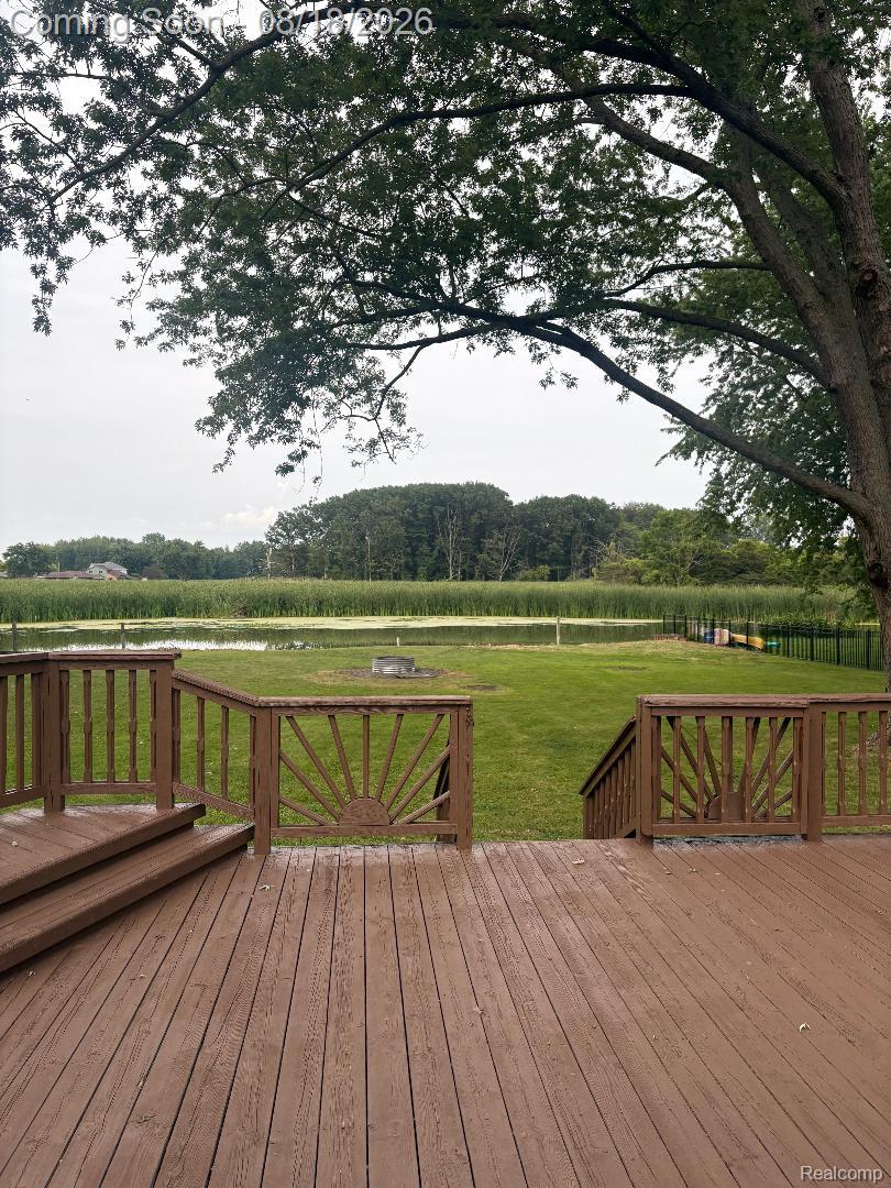 32563 Sutton Road New Baltimore, MI 48047 - Photo 10 of 43 Expansive wood deck with decorative railings, overlooking a manicured lawn, pond, and mature trees