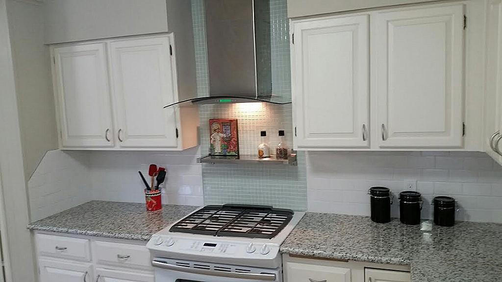 a kitchen with granite countertop stainless steel appliances white cabinets and a white stove