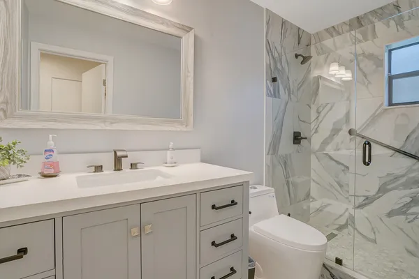 a bathroom with a granite countertop sink a toilet and a mirror