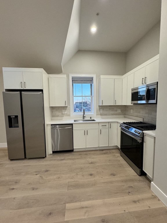 a kitchen with stainless steel appliances granite countertop a stove a sink dishwasher a refrigerator and a granite counter tops with wooden floors
