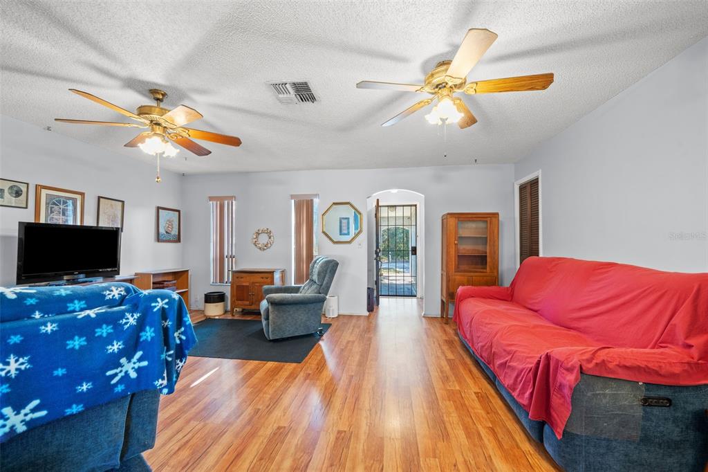 9061 Byron Street Spring Hill, FL 34606 - Photo 21 of 43 a living room with furniture a flat screen tv and a chandelier