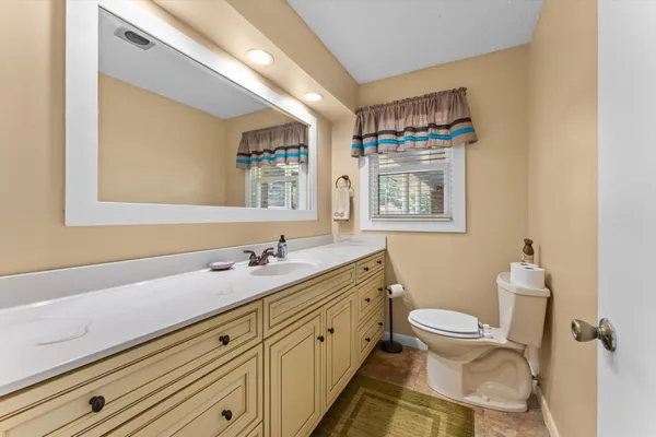 a bathroom with a double vanity sink toilet and a mirror