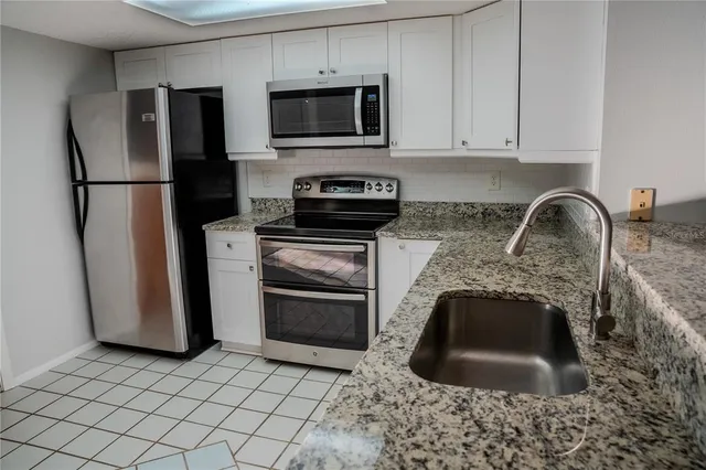 a kitchen with granite countertop a refrigerator and a sink