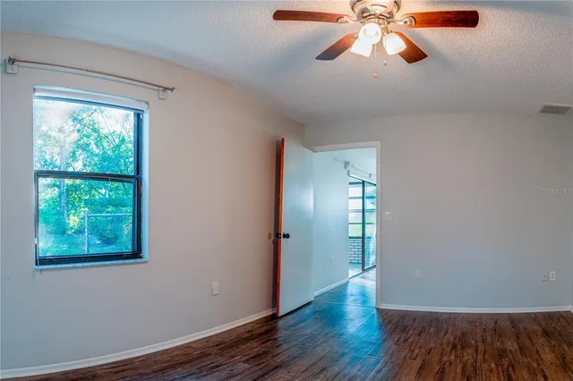 a view of empty room with wooden floor and fan