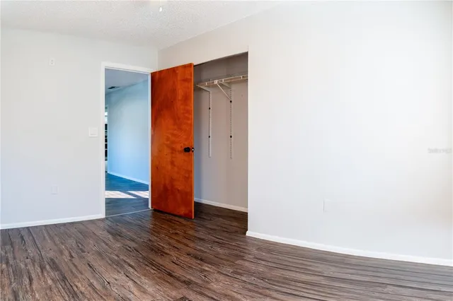 a view of an empty room with wooden floor and closet