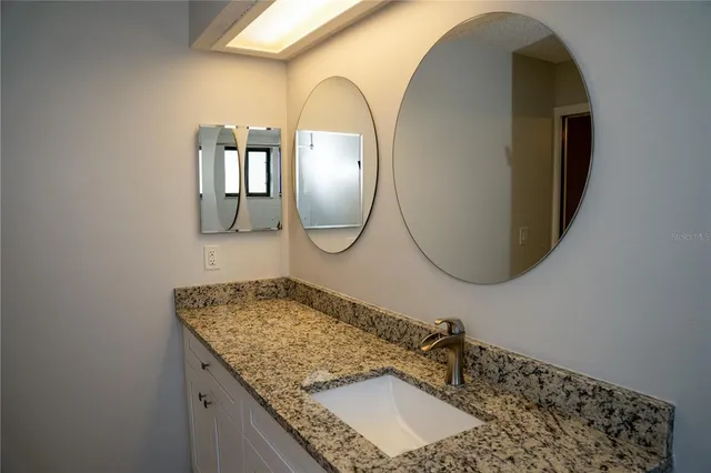 a bathroom with a granite countertop sink and a mirror