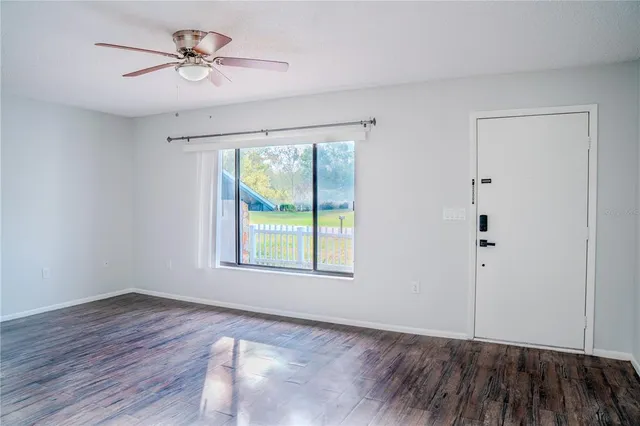 a view of an empty room with a window and wooden floor