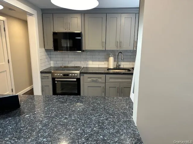 a kitchen with stainless steel appliances granite countertop a stove a sink and a microwave