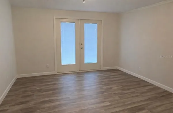 a view of an empty room with wooden floor and glass door