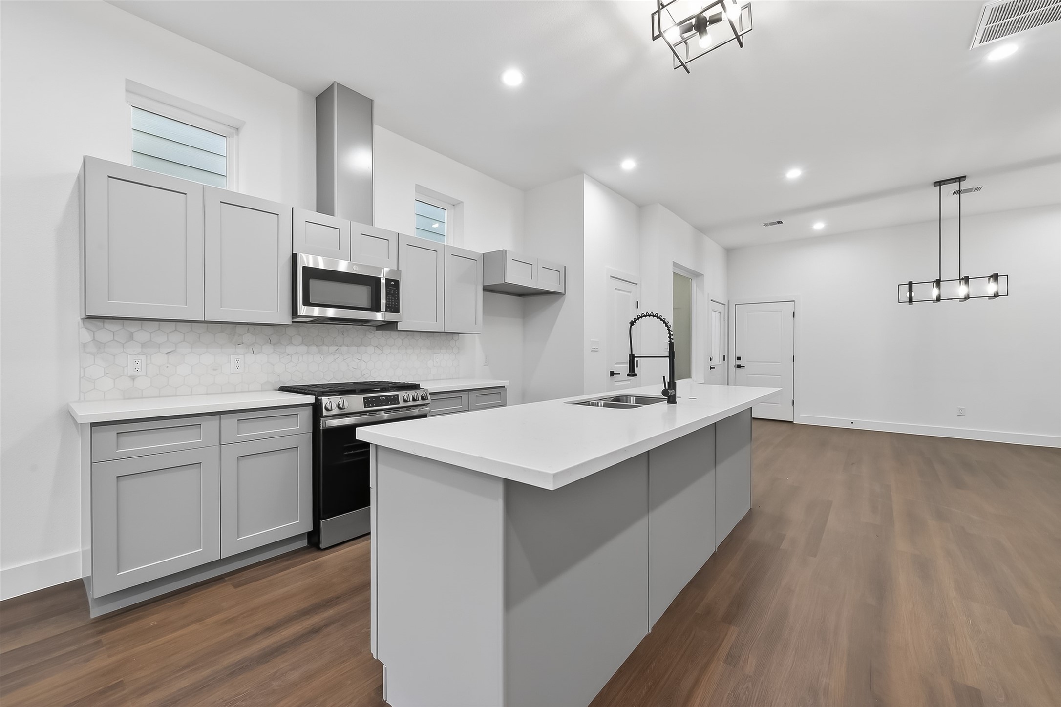 3514 Good Hope Street, Unit B Houston, TX 77021 - Photo 8 of 26 This modern kitchen features sleek gray cabinetry, stainless steel appliances, and a spacious island with a sink. The open layout flows into a bright, airy living area with contemporary lighting and hardwood floors. Perfect for entertaining.