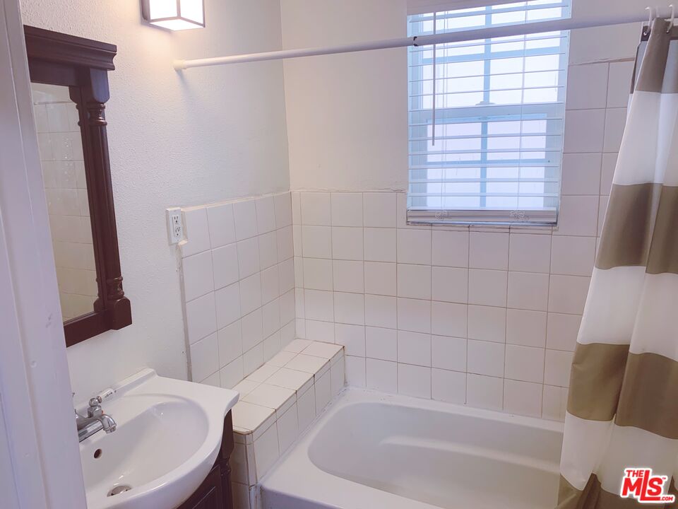 2740 James M Wood Boulevard Los Angeles, CA 90006 - Photo 12 of 15 a white bath tub sitting next to a white sink and vanity