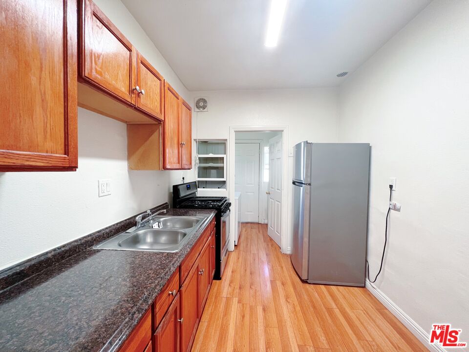 2740 James M Wood Boulevard Los Angeles, CA 90006 - Photo 6 of 15 a kitchen with stainless steel appliances granite countertop a refrigerator a stove and a wooden floor