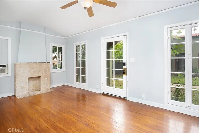 an empty room with windows fireplace and wooden floor