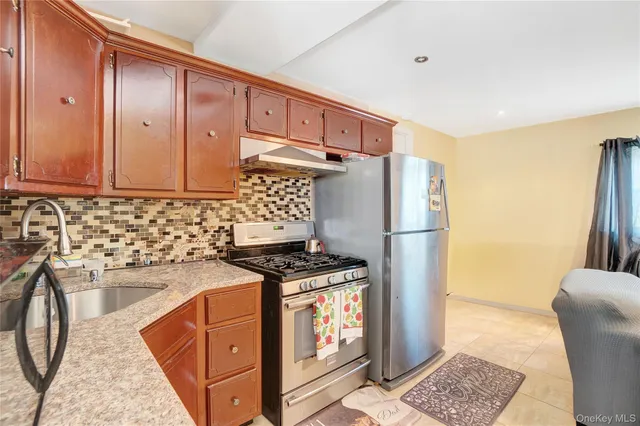 a kitchen with stainless steel appliances granite countertop a refrigerator a stove and a sink