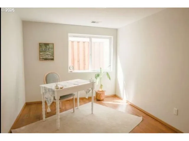 a living room with a table and a chair with wooden floor