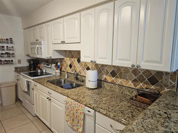 a kitchen with granite countertop a sink a stove and cabinets
