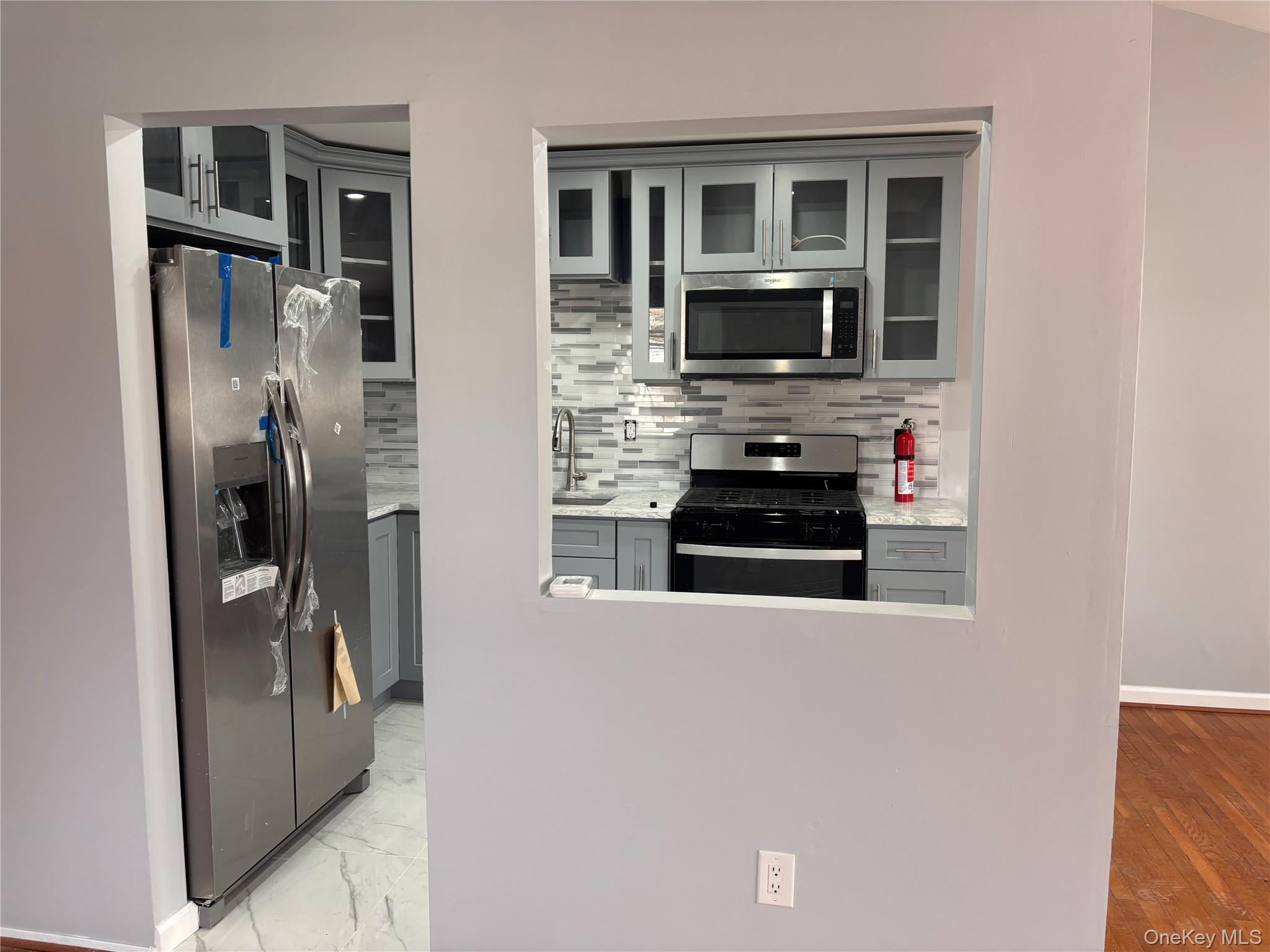 145-01 223rd Street, Unit 2 Queens, NY 11413 - Photo 3 of 12 a kitchen with stainless steel appliances a refrigerator and a stove top oven
