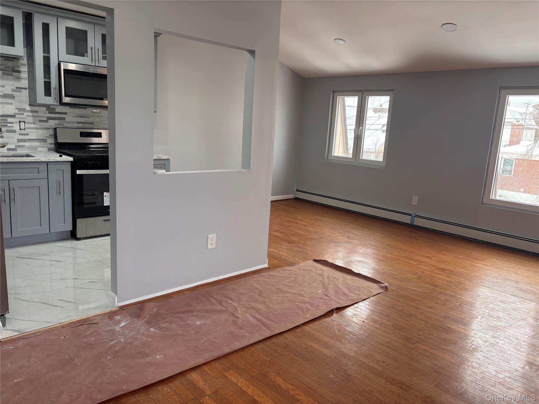145-01 223rd Street, Unit 2 Queens, NY 11413 - Photo 4 of 12 an empty room with wooden floor and windows