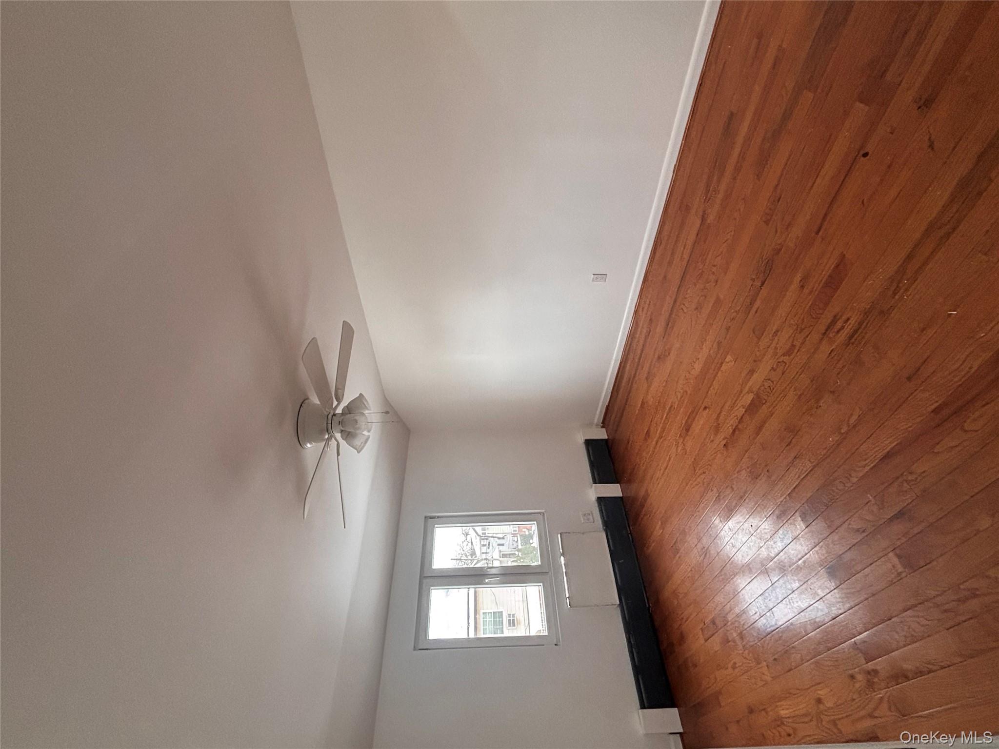 145-01 223rd Street, Unit 2 Queens, NY 11413 - Photo 6 of 12 an empty room with wooden floor and windows