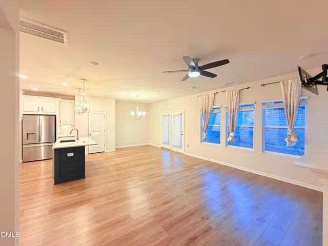 a view of an empty room with a kitchen and wooden floor