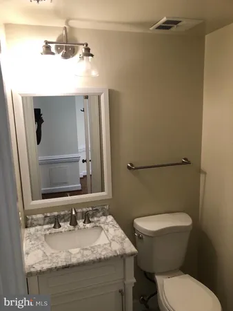 a bathroom with a granite countertop toilet sink and mirror