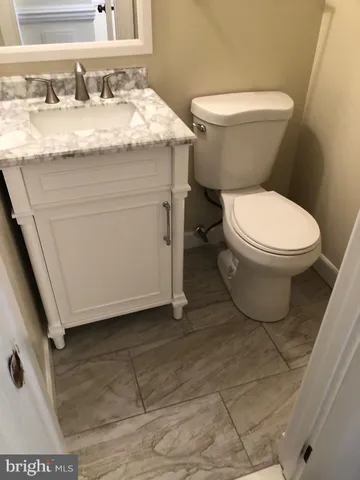 a bathroom with a granite countertop toilet sink and mirror