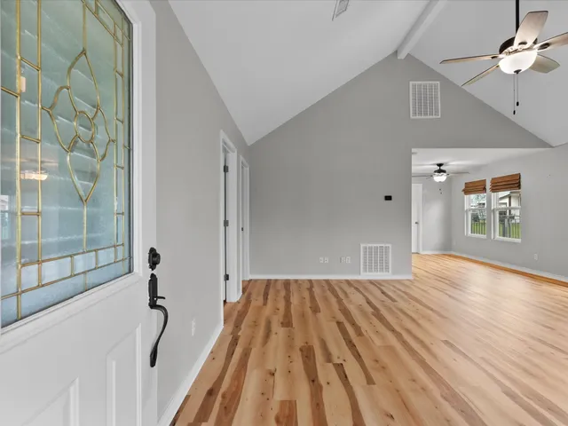 a view of empty room with wooden floor and fan
