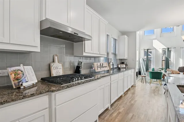 a kitchen with granite countertop a stove a sink dishwasher and cabinets with wooden floor