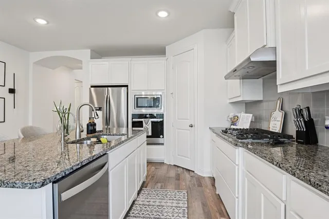 a kitchen with stainless steel appliances granite countertop a sink stove and refrigerator