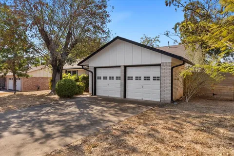 a view of a house with a large tree and wooden fence