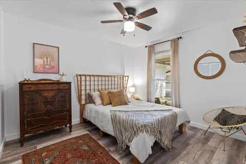 a bedroom with a bed and dresser with wooden floor