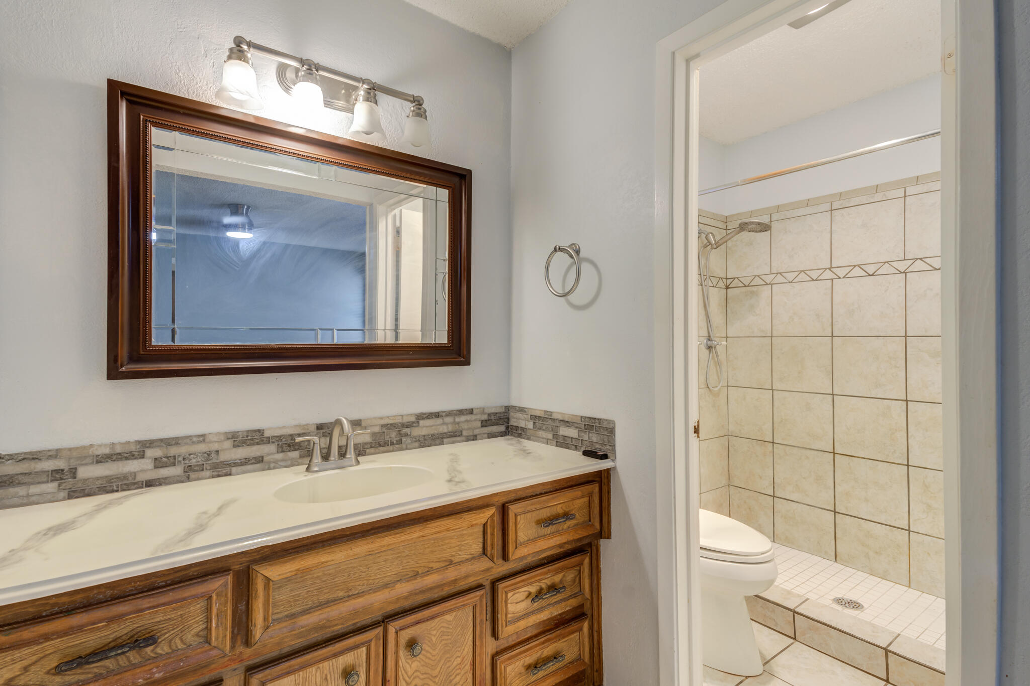 5018 70th Street Lubbock, TX 79424 - Photo 18 of 27 a bathroom with a granite countertop sink toilet and mirror