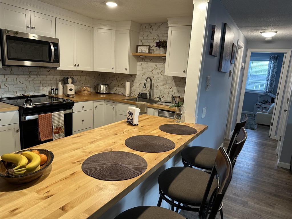 1475 Braley Road, Unit 17 New Bedford, MA 02745 - Photo 5 of 13 a kitchen with stainless steel appliances granite countertop a stove a sink a microwave and dining table