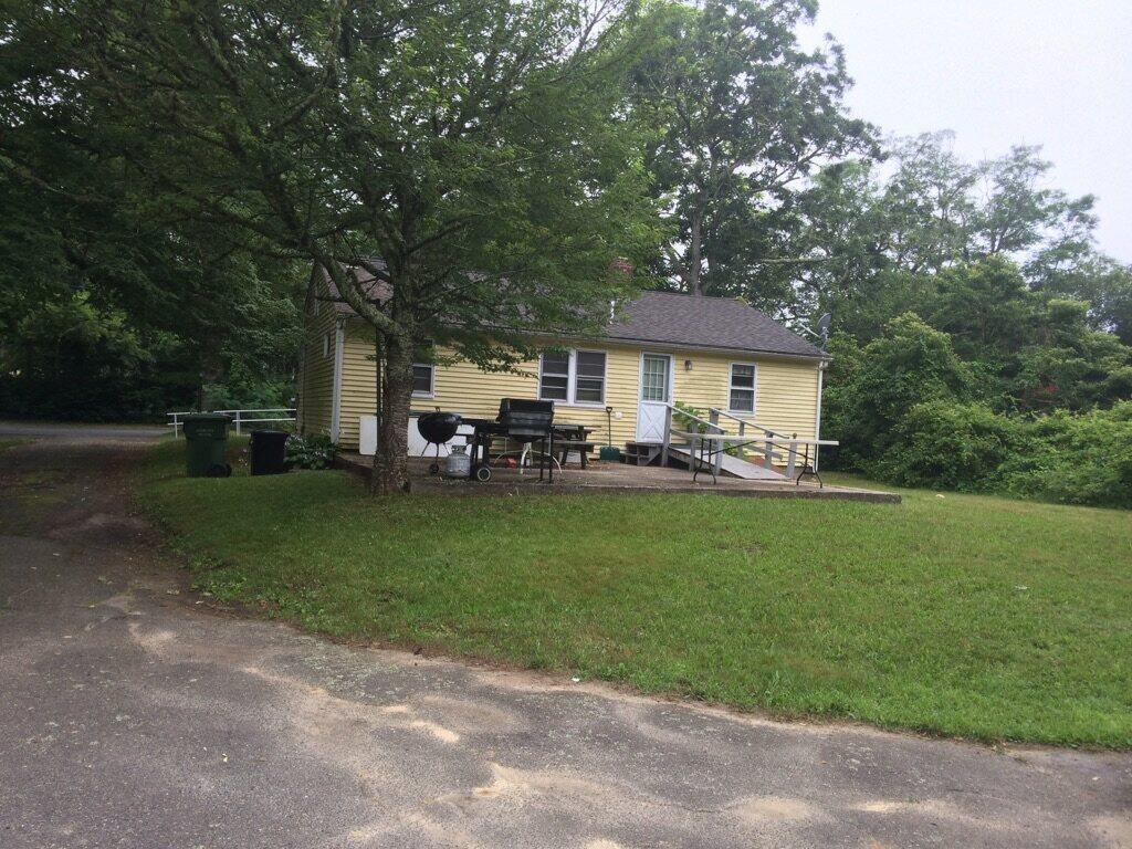 105 Main Street Mashpee, MA 02649 - Photo 7 of 8 a front view of a house with a garden and sitting area