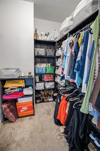 a view of walk in closet with clothes and shoes