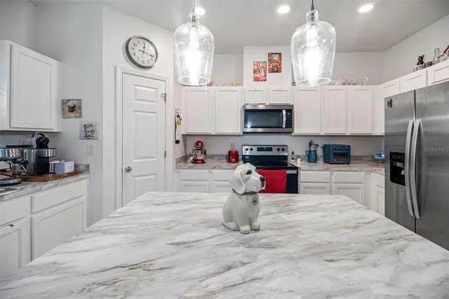 a kitchen with stainless steel appliances kitchen island granite countertop a refrigerator oven a stove top oven a sink and dishwasher