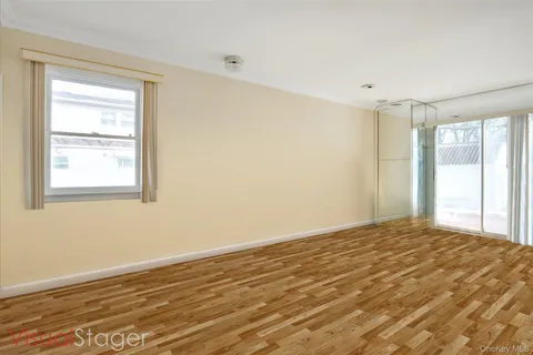 a view of an empty room with wooden floor and a window