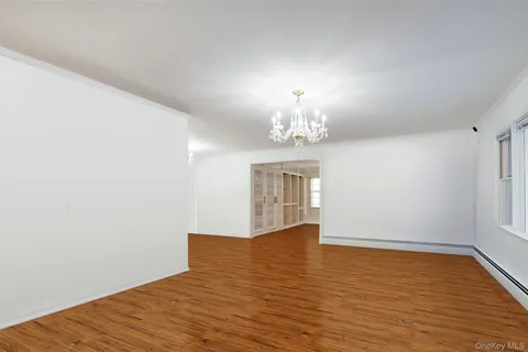 a view of an empty room with wooden floor and chandelier