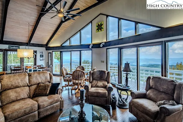a living room with furniture a ceiling fan and a large window
