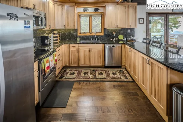 a view of a kitchen with stainless steel appliances granite countertop a stove a sink and a refrigerator