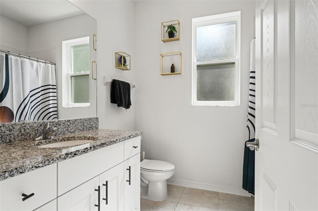 5945 Newberry Pnes Avenue Wesley Chapel, FL 33545 - Photo 23 of 55 a bathroom with a granite countertop sink a toilet and a mirror
